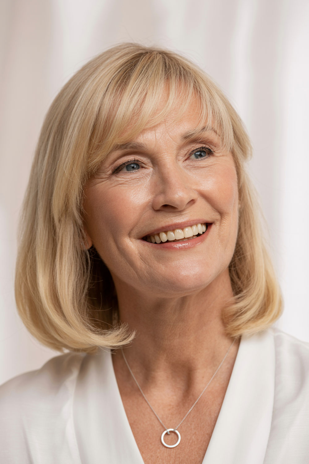 Older Woman With Soft Layered Bangs And Shoulder Length Blonde Hair Smiling Naturally